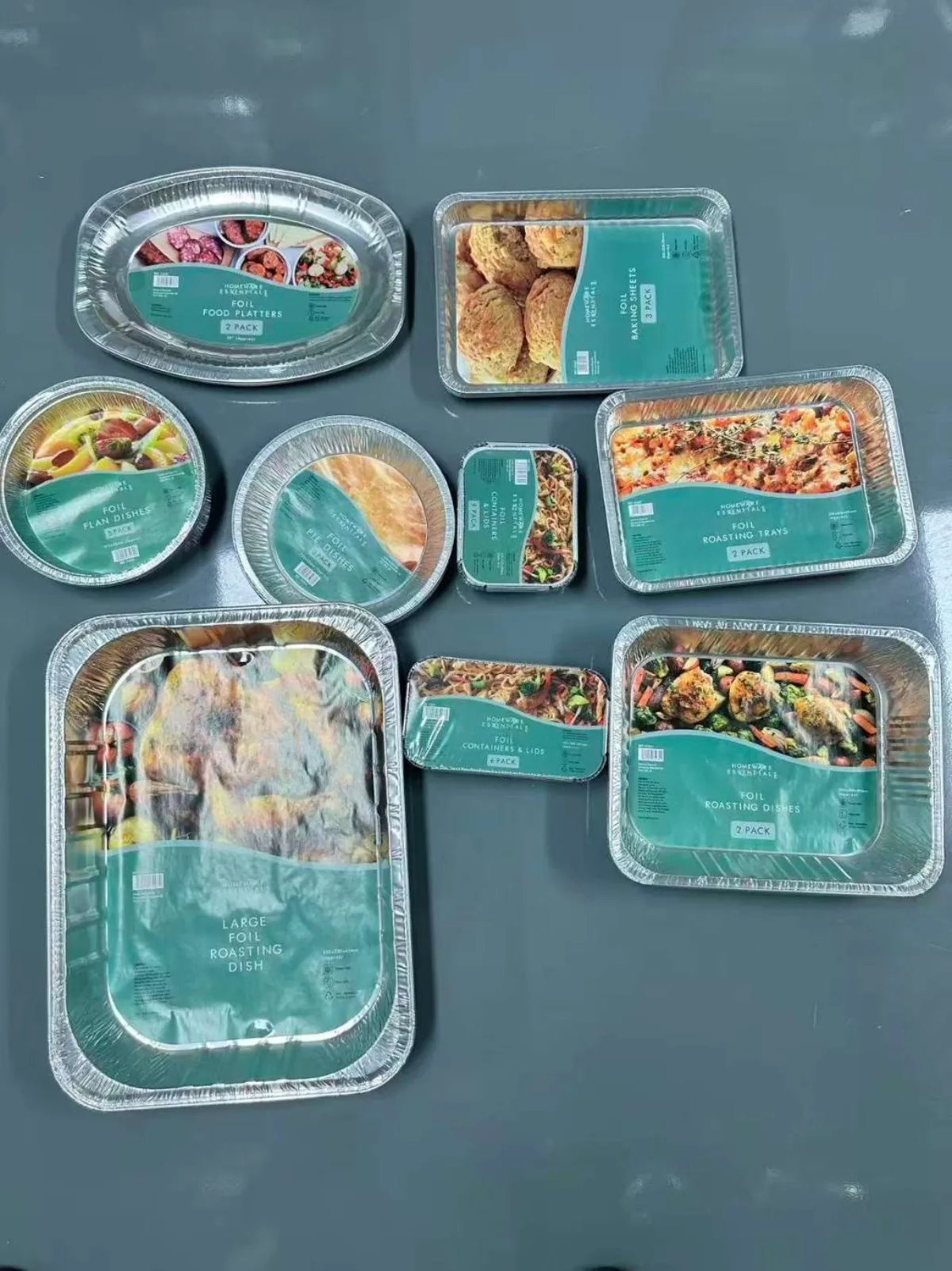 Aluminum foil take-out containers in assorted sizes, lids stacked beside